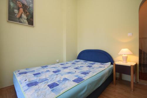 1 dormitorio con cama azul y mesa con lámpara en Apartments by the sea Podgora, Makarska - 2624, en Podgora