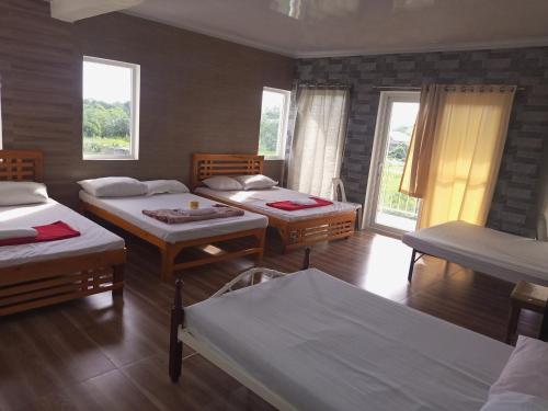 a room with four beds and windows in it at Villa Casa Camba, Barangay Bued in Alaminos