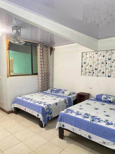 a bedroom with two beds with blue and white sheets at Blue Morpho House B&B in Manuel Antonio