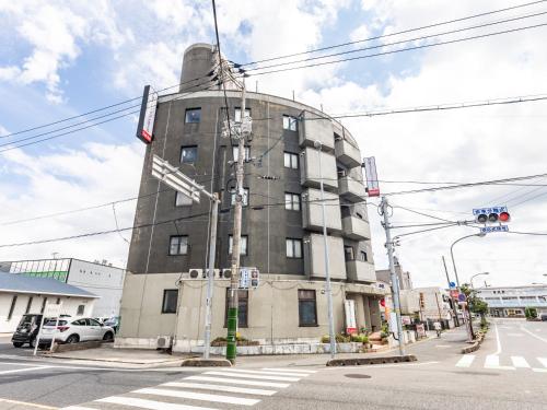 a tall building on a city street with a traffic light at Tabist Asa Station Hotel in Sanyoonoda