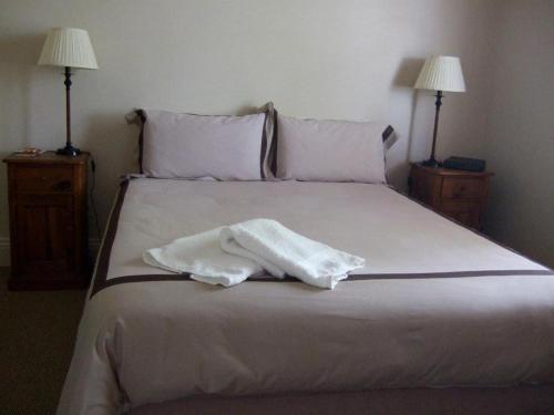 a white robe laying on a bed with two lamps at The Playhouse Hotel in Barraba