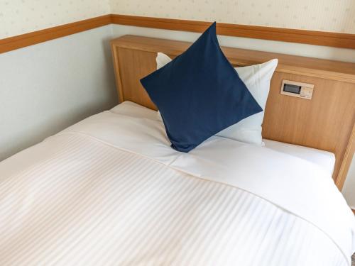 a blue pillow sitting on top of a bed at Tabist Asa Station Hotel in Sanyoonoda