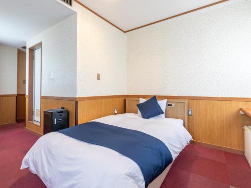 a bedroom with a large bed with a blue pillow at Tabist Asa Station Hotel in Sanyoonoda