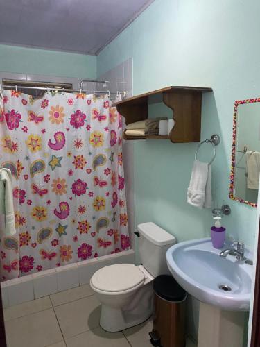 a bathroom with a toilet and a shower curtain at Blue Morpho House B&B in Manuel Antonio