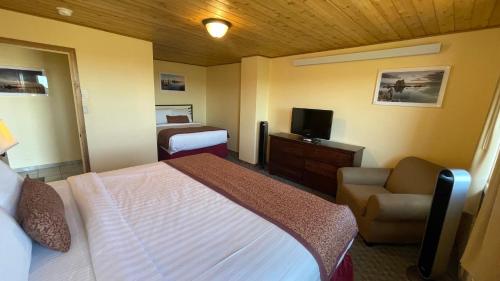 1 dormitorio con 1 cama, 1 silla y TV en Yosemite Gateway Motel, en Lee Vining