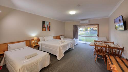 a hotel room with two beds and a table and chairs at Chinchilla Great Western Motor Inn in Chinchilla