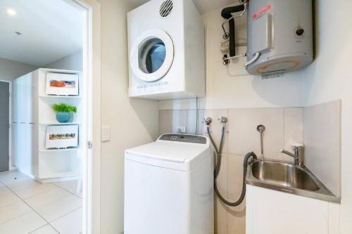 una pequeña cocina con lavadora y fregadero en 'Arafura Edge' Resort Lifestyle with 360 Views, en Darwin
