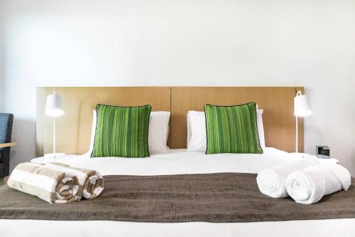 1 dormitorio con 1 cama grande con almohadas verdes en King Balcony Suite at Resort Style Darwin Stay, en Darwin