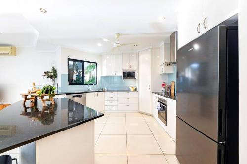 a kitchen with white cabinets and a stainless steel refrigerator at Luxe Bayview Oasis with Dream Waterfront Pool in Darwin