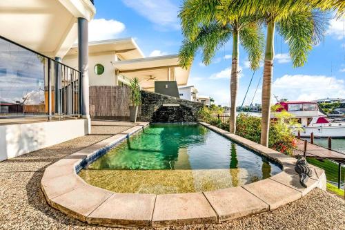 a swimming pool in the backyard of a house with palm trees at Luxe Bayview Oasis with Dream Waterfront Pool in Darwin