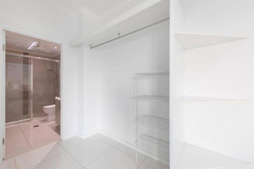 a white bathroom with a shower and a toilet at Sleek Penthouse Style meets Stunning Coastal Views in Nightcliff