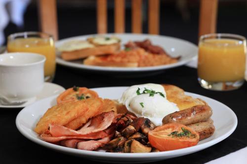two plates of breakfast food on a table with orange juice at Chinchilla Great Western Motor Inn in Chinchilla