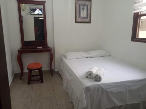 een slaapkamer met een bed, een kruk en een spiegel bij MyBestStay Piedra del Mar in Puerto López