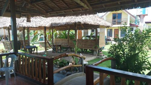 a porch with chairs and a thatch roof at Gardenview Homestay Siargao in General Luna