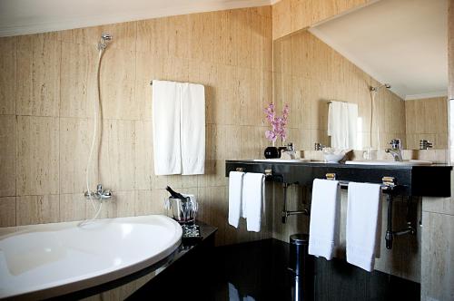 un bagno con una grande vasca bianca e due lavandini di Hotel Arumí a Santa Eugenia de Berga