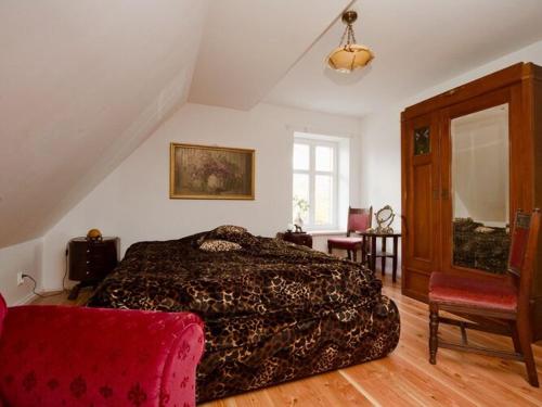 a bedroom with a large bed and a red chair at Historical holiday home in Mielenko 400 m from the sea in Mielenko