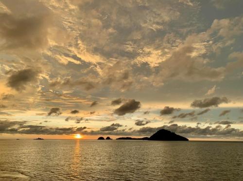 a sunset over a body of water with an island at Seaside Travellers Inn in Papar