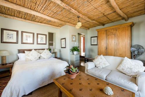 a bedroom with a white bed and a couch at The Oystercatchers Haven at Paternoster in Paternoster