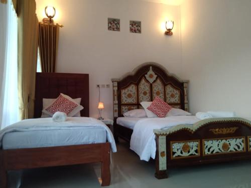 a bedroom with two beds and two lamps on the wall at Bintang Bungalow Tour & Travel in Kelimutu