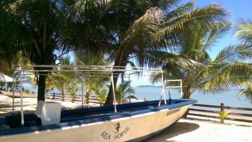 a boat sitting on the beach with palm trees at Seaside Travellers Inn in Papar
