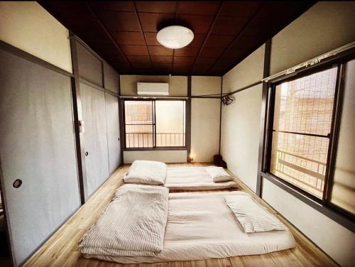 a room with four beds in it with two windows at 無料温泉チケット付 Oyado-Ichigo-Nie お宿一期二笑 #IG1 in Ito