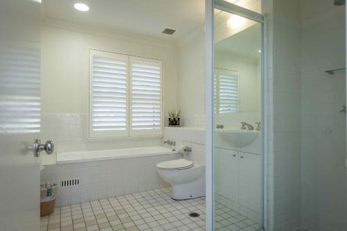 een witte badkamer met een toilet en een wastafel bij Villa Legato in Pokolbin