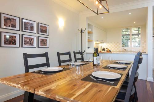 a dining room table with chairs and a bottle of wine at Villa Legato in Pokolbin