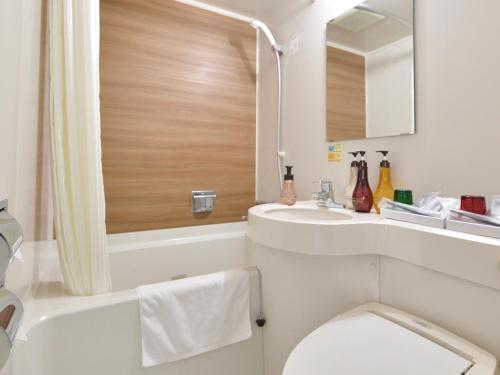a bathroom with a toilet and a sink and a mirror at Hotel WBF Kushiro in Kushiro