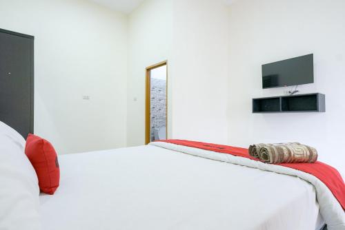 a bedroom with a white bed with a red pillow on it at RedDoorz @ Jalan Urip Sumoharjo Lampung in Kedaton