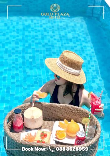 a girl in a hat sitting in a pool with a tray of food at Gold Plaza Hotel Da Nang in Da Nang