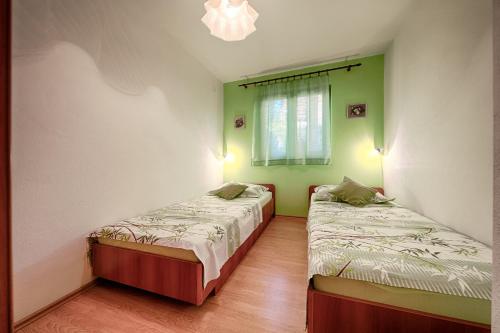 two beds in a room with green and white walls at Apartments by the sea Komiza, Vis - 2447 in Komiža