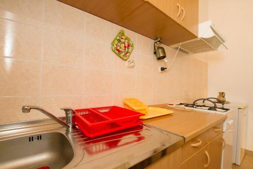 - un comptoir de cuisine avec un plateau rouge sur le évier dans l'établissement Apartments by the sea Milna, Vis - 2461, à Rukavac