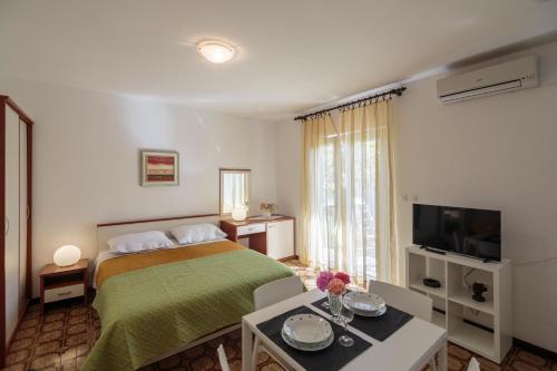 een slaapkamer met een bed, een tafel en een televisie bij Apartments with WiFi Komiza, Vis - 2420 in Komiža