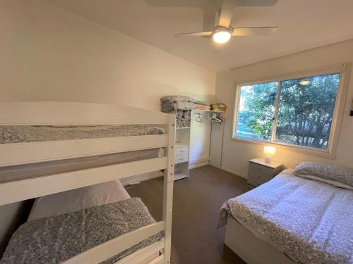 a bedroom with two bunk beds and a window at Elizabeth Beach Guest House in Elizabeth Beach