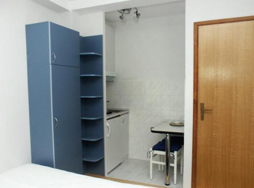 a small kitchen with a blue refrigerator and a table at Studio Komiza 2429e in Komiža