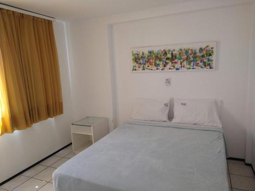 a bedroom with a white bed and a painting on the wall at Iracema Vista sensacional 4 pessoas in Fortaleza