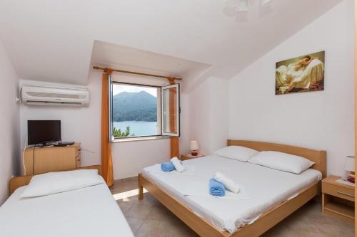 two beds in a room with a window at Apartments and rooms by the sea Slano, Dubrovnik - 2687 in Slano