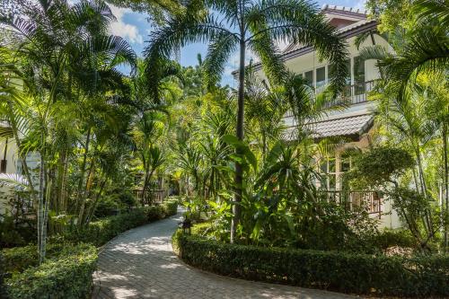 a path lined with palm trees in front of a building at Laksasubha Hua Hin in Hua Hin