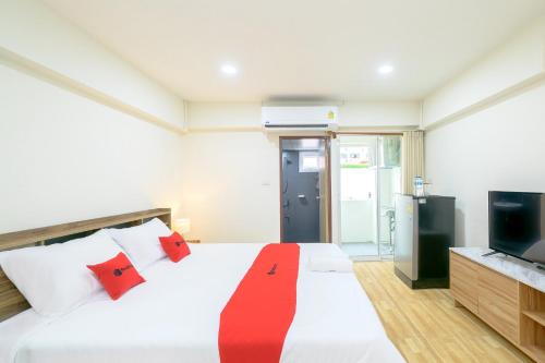 a bedroom with a bed with red pillows and a television at Hoenhao Boutique Ratchada in Bang Su