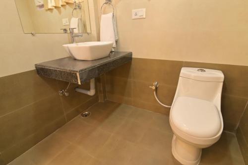 a bathroom with a white toilet and a sink at The Sumola House in Jorhāt