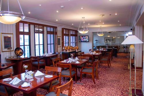 a restaurant with wooden tables and chairs and windows at Redtop Hotel & Convention Center in Jakarta