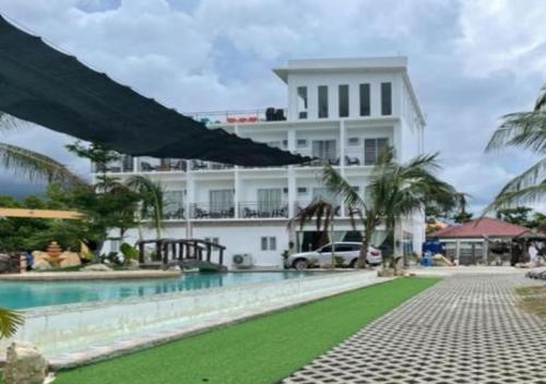 un gran edificio blanco con una piscina frente a él en RedDoorz at PWL Exclusive Resort Cebu en Carmen