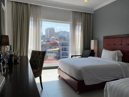a hotel room with a bed and a desk and a window at Queenco Hotel & Casino in Sihanoukville