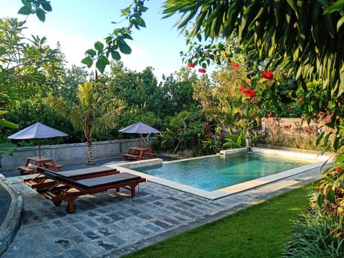 チャングーにあるKubu Jasmine Baliのラウンジ2つとパラソル付きの庭園内のスイミングプール