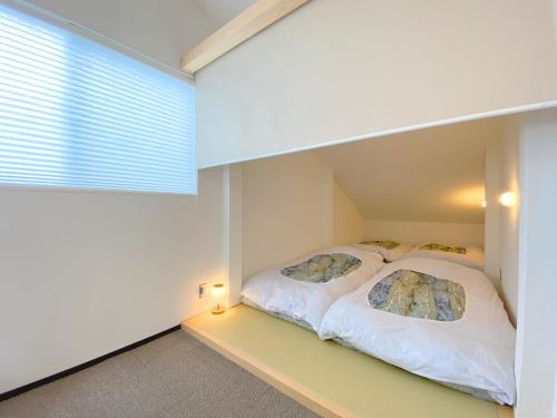 Duas camas num quarto branco com uma janela em Joka Base em Kakegawa