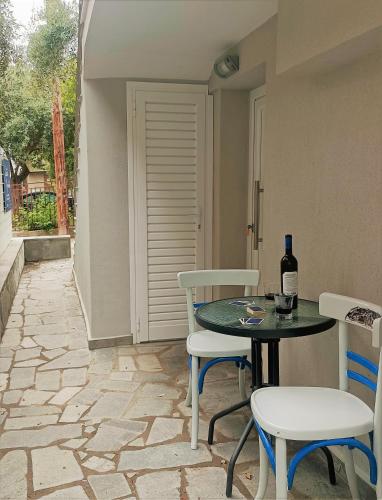 a patio with a table and chairs and a bottle of wine at Spitaki Apartments Potos in Potos
