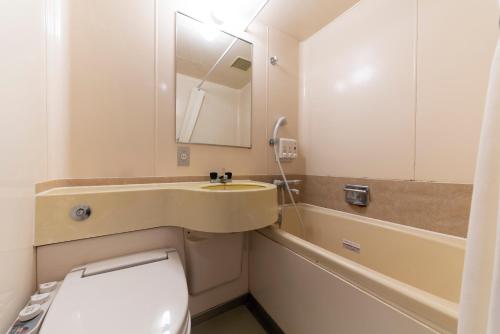 a bathroom with a toilet and a sink and a mirror at Hotel Econo Kanazawa Station in Kanazawa