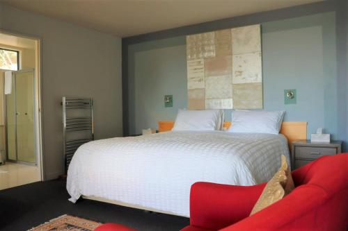 a bedroom with a large bed and a red couch at Armalong Winery Chalets in Rosevears