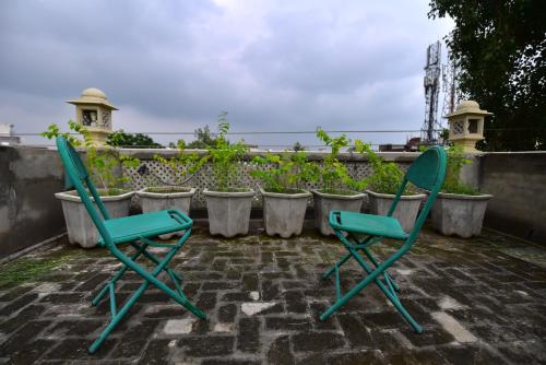 two green chairs sitting on a patio with potted plants at Stay Shaandaar a boutique hotel Amritsar in Amritsar
