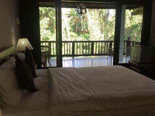 1 dormitorio con 1 cama grande y balcón en Raka Rai Bungalows en Ubud